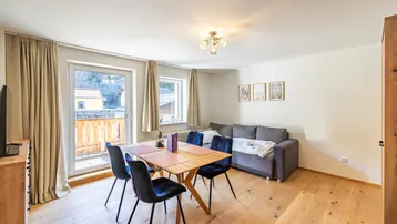 Heller Wohn- und Essbereich mit Holzboden, Esstisch und Zugang zu einem Balkon.