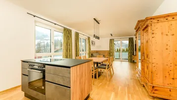 Moderne offene Küche mit Kochinsel, Essbereich und Blick auf die umliegende Berglandschaft.