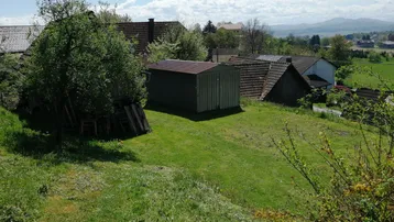 Gartenbereich mit Schuppen und Blick auf die umliegende Landschaft und Berge.