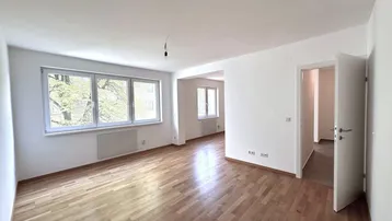 Heller Wohnbereich mit Parkettboden und Zugang zu weiteren Räumen, ideal für offenes Wohnen.