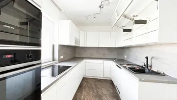 Moderne Einbauküche in Weiß mit grauer Arbeitsplatte, integrierten Siemens-Geräten und Induktionskochfeld.