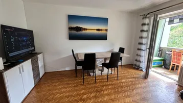 Heller Wohn- und Essbereich mit Parkettboden, Esstisch und Zugang zum Balkon.