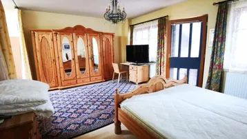 Geräumiges Schlafzimmer mit traditionellen Holzmöbeln, großem Kleiderschrank und Kronleuchter.