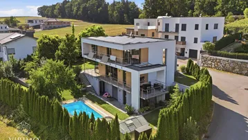 Moderne Villa mit Pool und gepflegtem Garten in ländlicher Umgebung, umgeben von viel Grün.