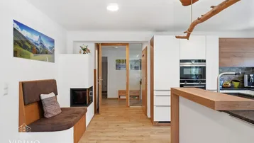 Gemütlicher Küchenbereich mit modernem Kaminofen, integrierter Sitzbank und Holzboden.