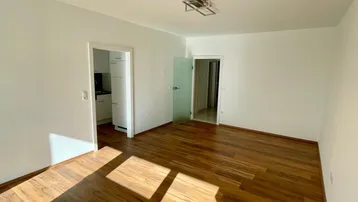 Helles Zimmer mit Holzboden und weißen Wänden, bereit zur individuellen Gestaltung.