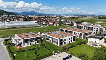 Weitläufige Ansicht der Wohnanlage mit umliegender Landschaft und Bergen im Hintergrund.