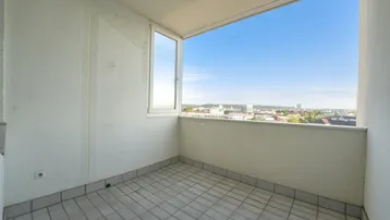 Heller Balkon mit Fliesenboden und weitem Blick über die Stadtlandschaft.