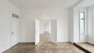 Helles Zimmer mit Fischgrätparkett und hohen Türen, bereit zur individuellen Gestaltung.