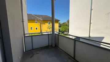 Kleiner Balkon mit Fliesenboden und Blick auf die umliegenden Gebäude und Grünflächen.