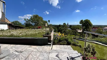 Große Steinterrasse mit Panoramablick über die Landschaft und ein Dorf mit Kirchturm.