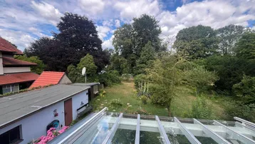 Weitläufiger Gartenbereich mit altem Baumbestand und Blick auf ein Nebengebäude.