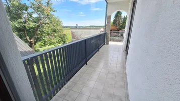 Langer Balkon mit Fliesenboden und dunklem Geländer, bietet weite Aussicht.