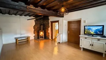 Gemütliches Wohnzimmer mit Holzbalkendecke, Kaminofen und rustikalen Möbeln.