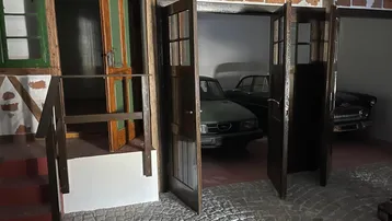 Thematischer Innenraum mit rustikalen Holztüren, einer kleinen Treppe und Oldtimern im Hintergrund.