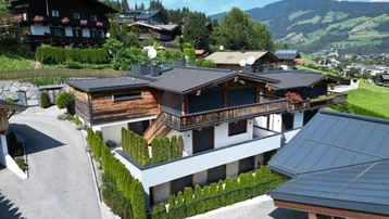 Moderne Chalet-Architektur mit Holzfassade und gepflegter Außenanlage in alpiner Umgebung.