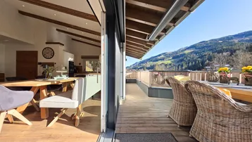 Geräumige Holzterrasse mit Sitzgelegenheiten und weitem Blick auf die umliegende Berglandschaft.