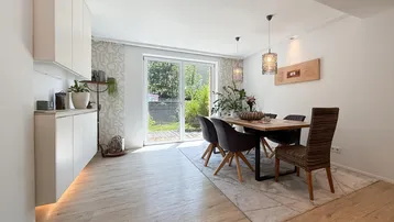 Heller Essbereich mit Holzboden, modernen Möbeln und Zugang zum Garten.