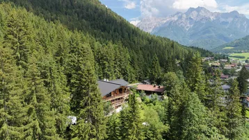 Großzügiges Anwesen umgeben von dichtem Wald mit Bergblick und traditioneller Holzarchitektur.