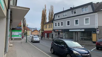 Blick auf eine belebte Straße mit traditionellen Gebäuden und Mansarddach in einer städtischen Umgebung.