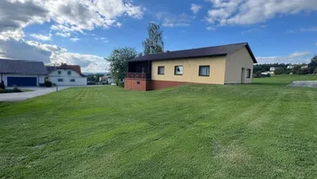 Weitläufiger Blick auf das Einfamilienhaus mit großem Rasen und ländlicher Umgebung.