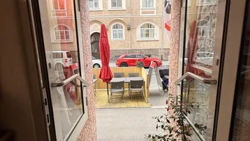 Blick aus dem Eingangsbereich eines Restaurants auf die Straße mit Außenterrasse und Tischen.
