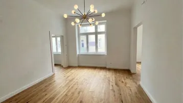 Helles, frisch renoviertes Zimmer mit neuem Parkettboden und moderner Deckenleuchte.