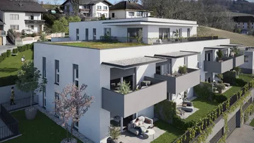 Moderne Wohnanlage mit Terrassen, Balkonen und begrünten Außenbereichen in sonniger Hanglage.
