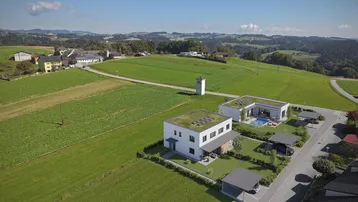 Luftaufnahme von zwei modernen Häusern mit Gründächern in ländlicher Umgebung mit Feldern.