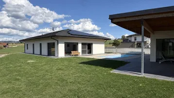 Weitläufiger Garten mit Swimmingpool und moderner Architektur des Hauses im Hintergrund.