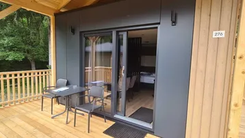 Möblierte Holzterrasse mit Schiebetüren, die in das moderne Ferienhaus führen.