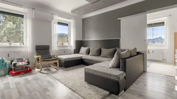 Helles Wohnzimmer mit großem Ecksofa, modernem Decken-Design und Blick ins Grüne.