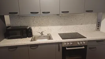 Moderne Küche mit grauen Schränken, Induktionskochfeld, Backofen und Mikrowelle, ideal für den täglichen Gebrauch.