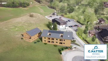 Luftaufnahme eines modernen Wohngebäudes mit Photovoltaikanlage in ländlicher Umgebung.