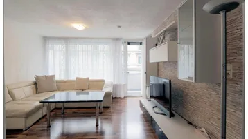 Helles Wohnzimmer mit beigem Sofa, Holzboden und einer modernen Steinwand als Akzent.
