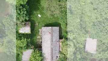 Luftaufnahme eines länglichen Grundstücks mit Bestandsgebäuden und viel Grünfläche, angrenzend an eine Straße.