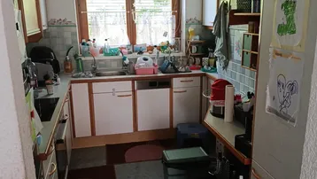 Küche mit U-förmiger Anordnung, Holzschränken, gefliestem Spritzschutz und einem Fenster.