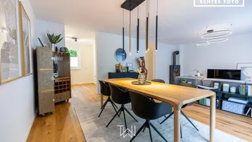 Moderner Essbereich mit Holztisch, Designerstühlen und stilvoller Beleuchtung, angrenzend an den Wohnbereich.