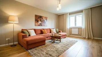 Gemütliches Wohnzimmer mit beigefarbenen Wänden, großem Ecksofa und hellem Holzboden.
