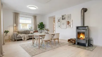 Helles Wohn- und Esszimmer mit modernem Kaminofen, Holzboden und stilvoller Einrichtung.