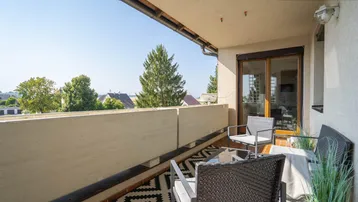 Geräumiger Balkon mit Sitzgelegenheiten und Blick ins Grüne, ideal zum Entspannen im Freien.