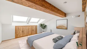 Helles Schlafzimmer im Dachgeschoss mit Holzbalken, Dachfenstern und Einbauschränken.
