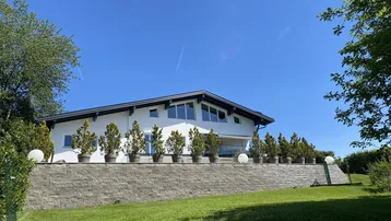 Modernes Wohnhaus mit weißer Fassade und gepflegter Außenanlage unter blauem Himmel.