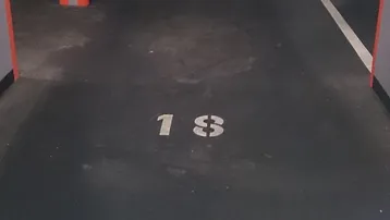 Tiefgaragenstellplatz mit Nummer 18, grauen Wänden und orange gestreiften Säulen.