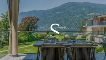 Geräumige Terrasse mit Esstisch und Stühlen, bietet einen atemberaubenden Blick auf den See und die Berge.