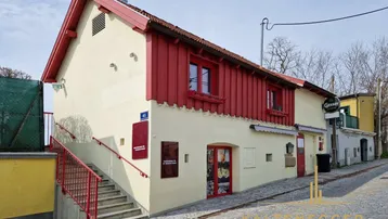Traditionelles Gebäude mit roter Holzverkleidung und beiger Fassade an einer gepflasterten Straße.