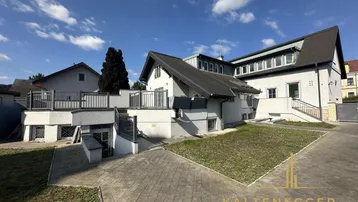 Großzügiges Anwesen mit mehreren Ebenen und Terrassenbereichen unter blauem Himmel.