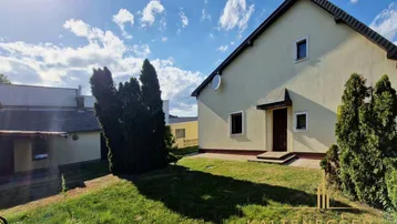 Außenansicht des Hauses mit gepflegtem Rasen und sonnigem Himmel.