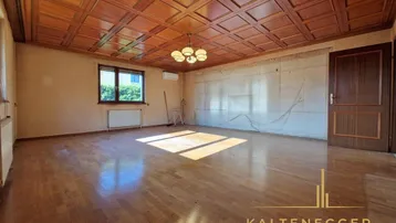 Großes leeres Zimmer mit Parkettboden und einer beeindruckenden Holz-Kassettendecke.