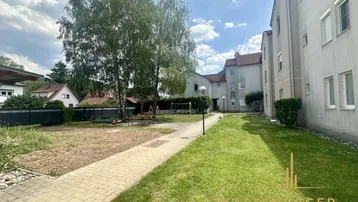 Gemeinschaftlicher Gartenbereich mit Rasenfläche, Spielplatz und Bäumen zwischen den Wohngebäuden.